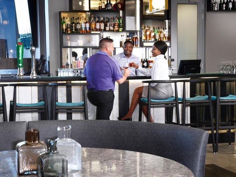 A modern, well-appointed bar area featuring a marble-look counter, professional back-bar shelving, and integrated lighting, suitable for social gatherings.