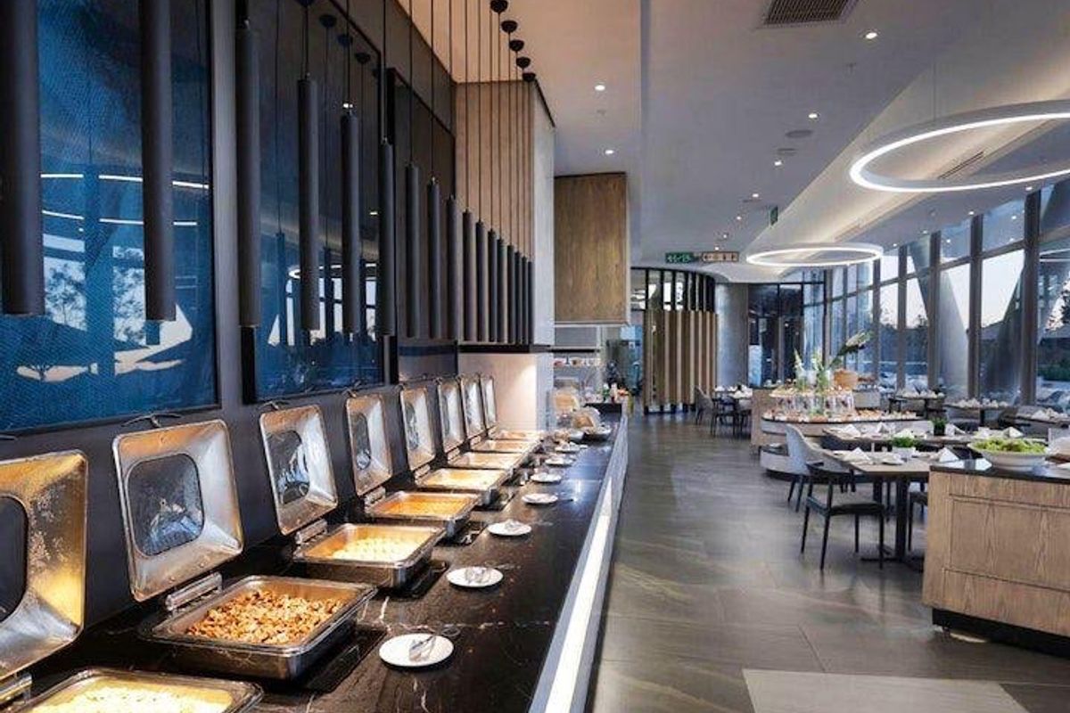 Modern clubhouse dining area featuring a sleek black marble buffet station, contemporary pendant lighting, and expansive floor-to-ceiling windows.
