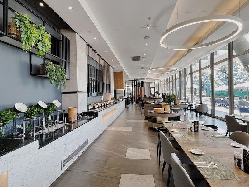 Modern open-plan dining and buffet area featuring high-end marble finishes, floor-to-ceiling windows, and contemporary architectural lighting.