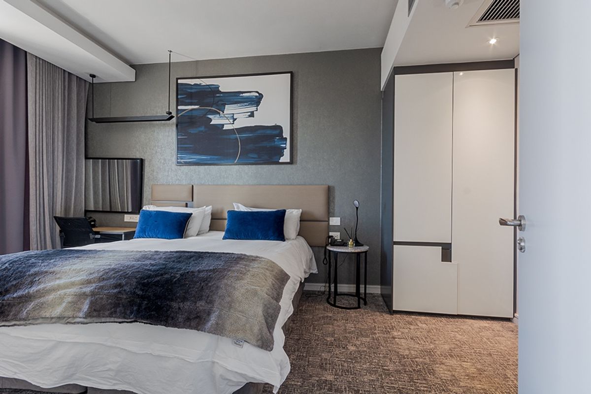 A well-appointed bedroom featuring a built-in wardrobe, recessed ceiling lighting, and integrated air conditioning, offering a modern and comfortable living space.