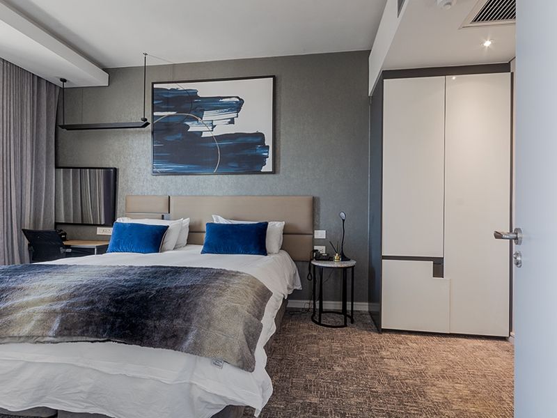 A well-appointed bedroom featuring a built-in wardrobe, recessed ceiling lighting, and integrated air conditioning, offering a modern and comfortable living space.