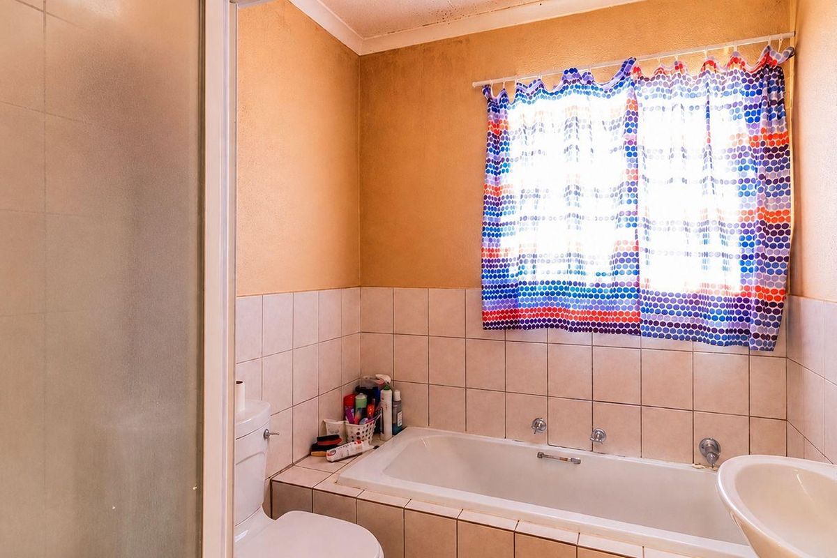 A functional bathroom featuring a built-in bathtub, pedestal basin, toilet, and separate shower enclosure, requiring cosmetic updates to the wall finishes and tiling.