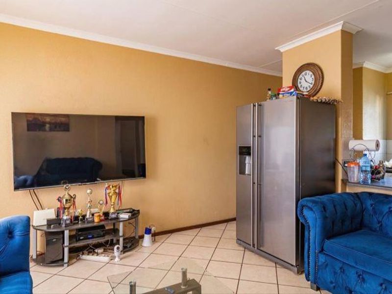 Open plan living area featuring tiled flooring and a breakfast bar connecting to the kitchen space.