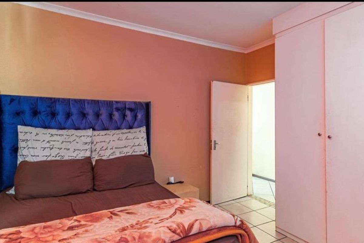 A bedroom featuring built-in wardrobes and tiled flooring, offering a functional space with potential for cosmetic updates.