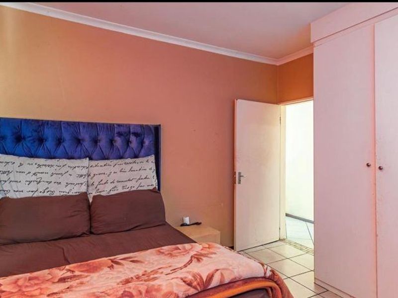 A bedroom featuring built-in wardrobes and tiled flooring, offering a functional space with potential for cosmetic updates.