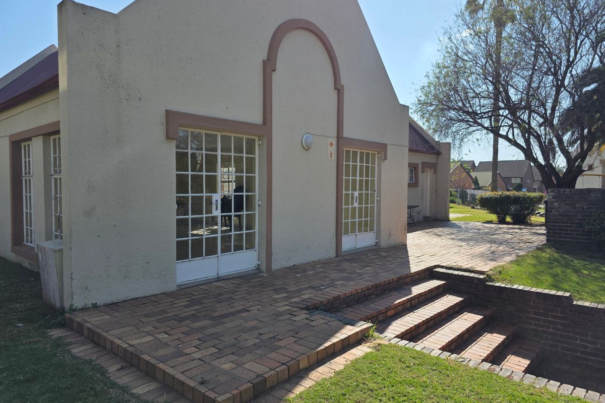 Rear view of the apartment featuring a brick-paved patio area with steps leading to double french door entrances.