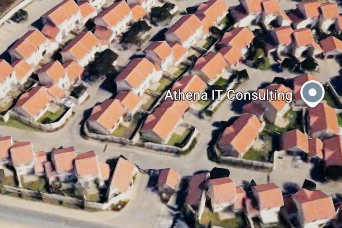 An aerial view of a residential townhouse complex featuring multiple units with tiled roofs and perimeter boundary walls.