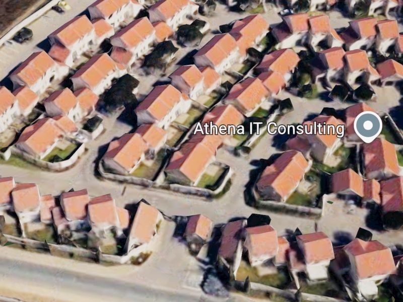 An aerial view of a residential townhouse complex featuring multiple units with tiled roofs and perimeter boundary walls.