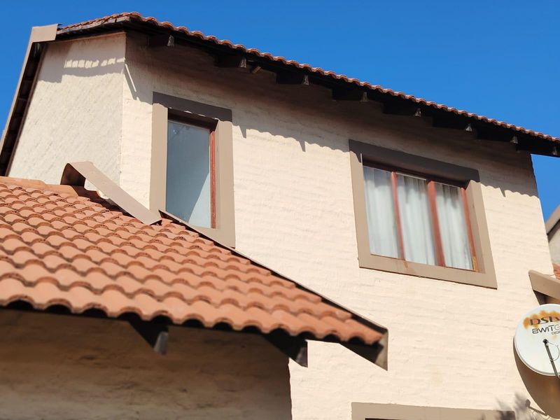 Exterior view of a townhouse featuring a terracotta tiled roof, plastered walls, and timber-framed windows.