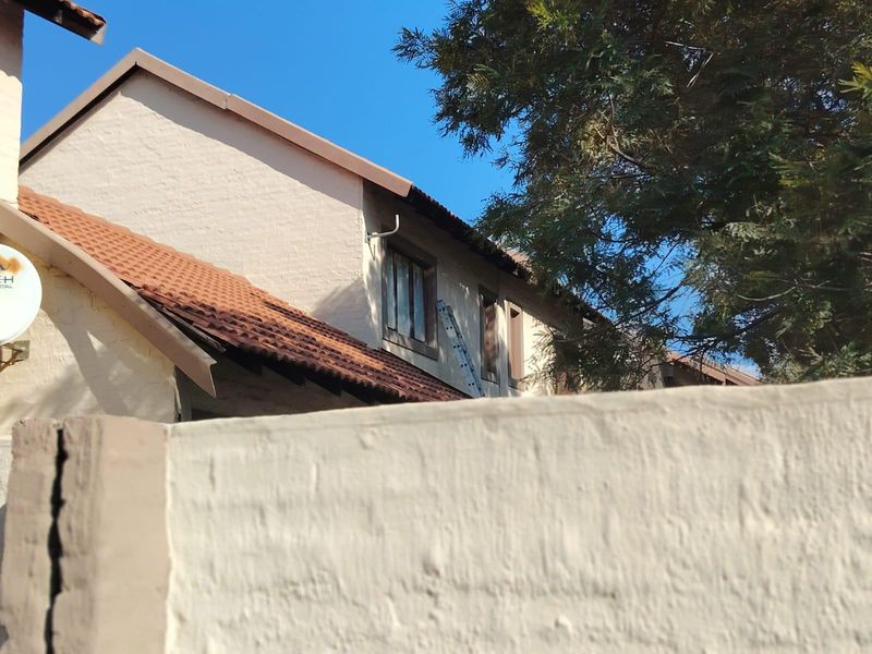 Rear exterior view of the townhouse showing plastered walls and terracotta roof tiles with visible signs of roof maintenance required.