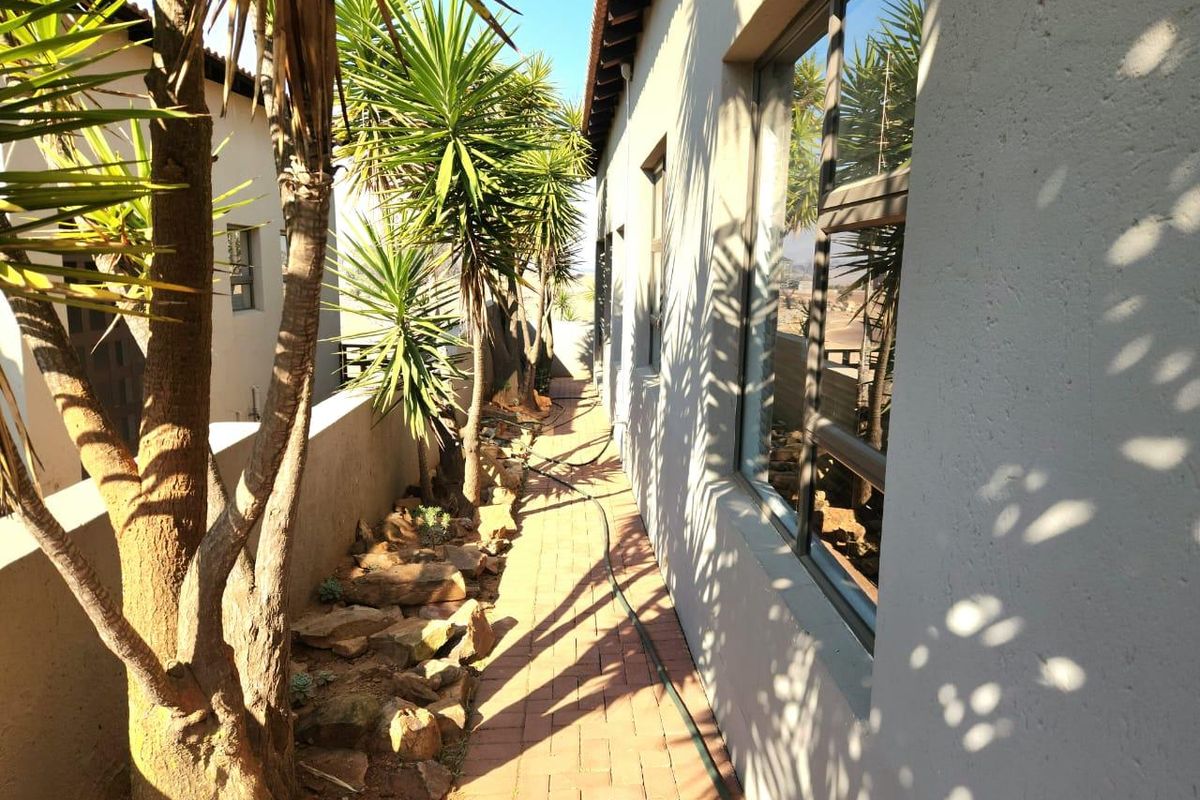 A side walkway featuring brick paving, a low retaining wall, and established landscaping alongside the exterior wall of the house.