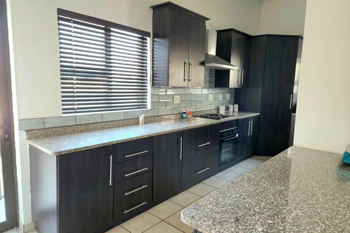 Modern kitchen featuring dark wood cabinetry, granite countertops, subway tile backsplash, and integrated appliances including an oven and extractor fan.