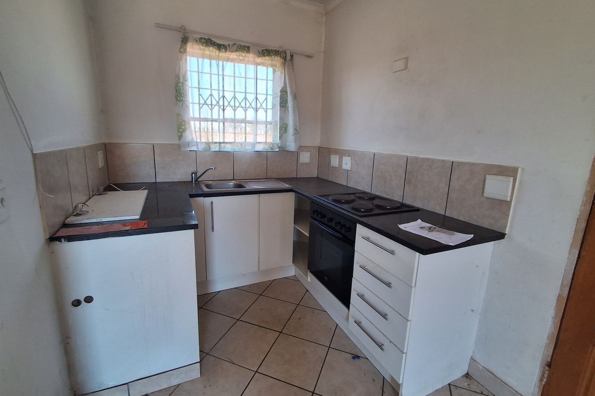 Compact kitchen featuring built-in cabinetry, laminate countertops, integrated oven and hob, and tiled flooring. Requires cosmetic updates to improve overall appeal.