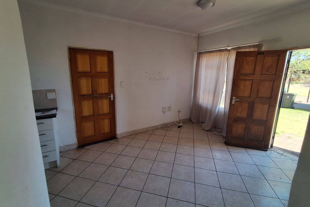 An empty living area featuring tiled flooring and timber panel doors with direct access to the exterior.