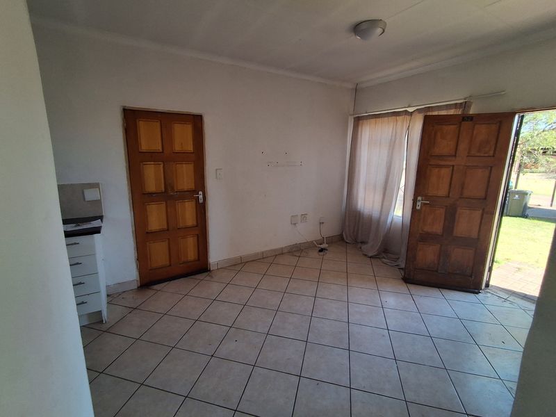 An empty living area featuring tiled flooring and timber panel doors with direct access to the exterior.