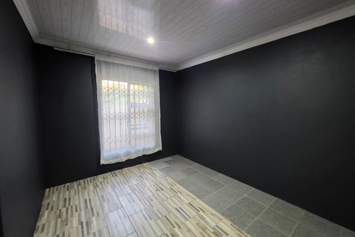 An empty bedroom featuring dark painted walls, a coved ceiling with recessed lighting, and a combination of two different styles of floor tiles.
