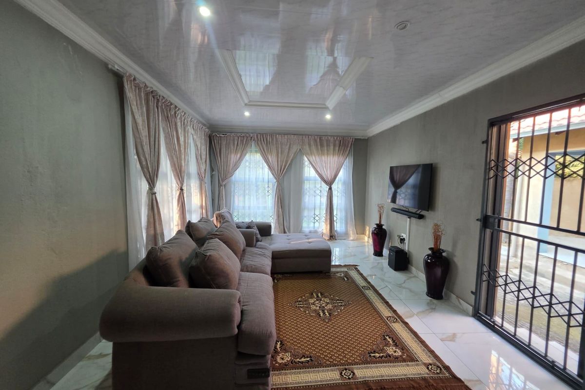 A modern living room featuring glossy ceiling finishes, recessed lighting, and polished marble-look floor tiles with a secure entrance gate.