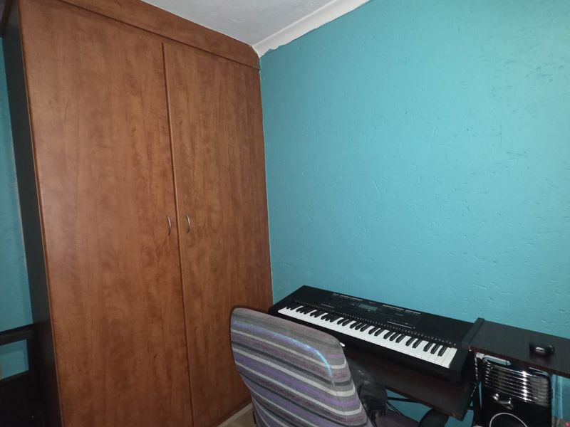 A bedroom featuring a built-in wooden wardrobe, laminate flooring, and a vibrant blue accent wall.