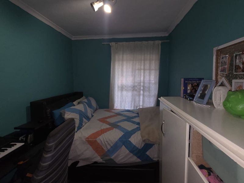 A compact bedroom featuring teal painted walls, a central ceiling spotlight fixture, and decorative coving.