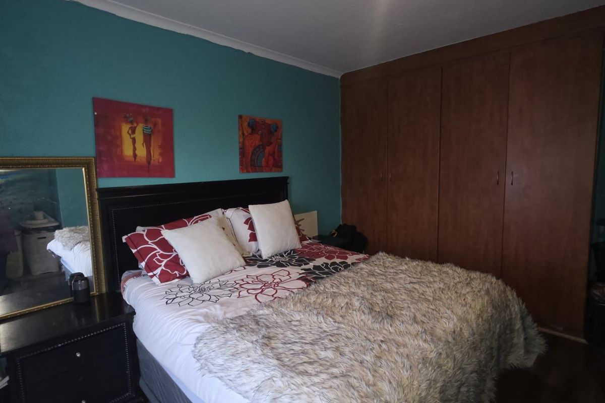 A bedroom featuring built-in wooden cupboards and a teal accent wall.