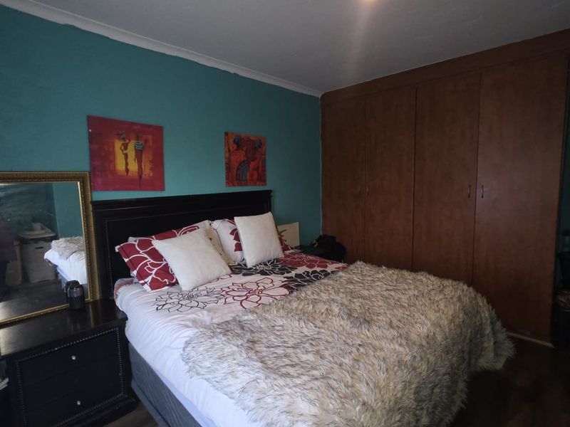A bedroom featuring built-in wooden cupboards and a teal accent wall.