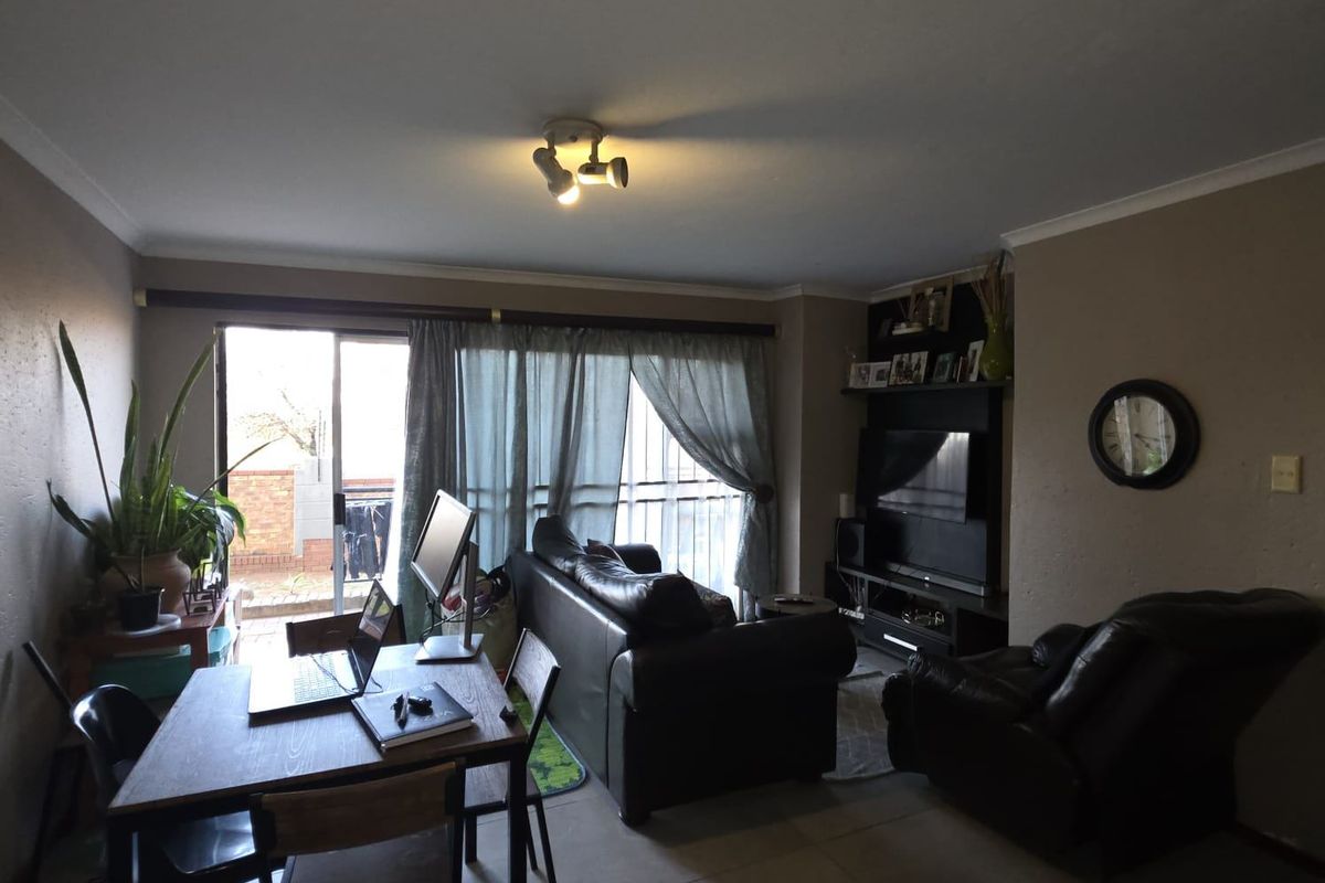 A living room featuring tiled flooring, a built-in media unit, and a sliding glass door providing access to an outdoor area.