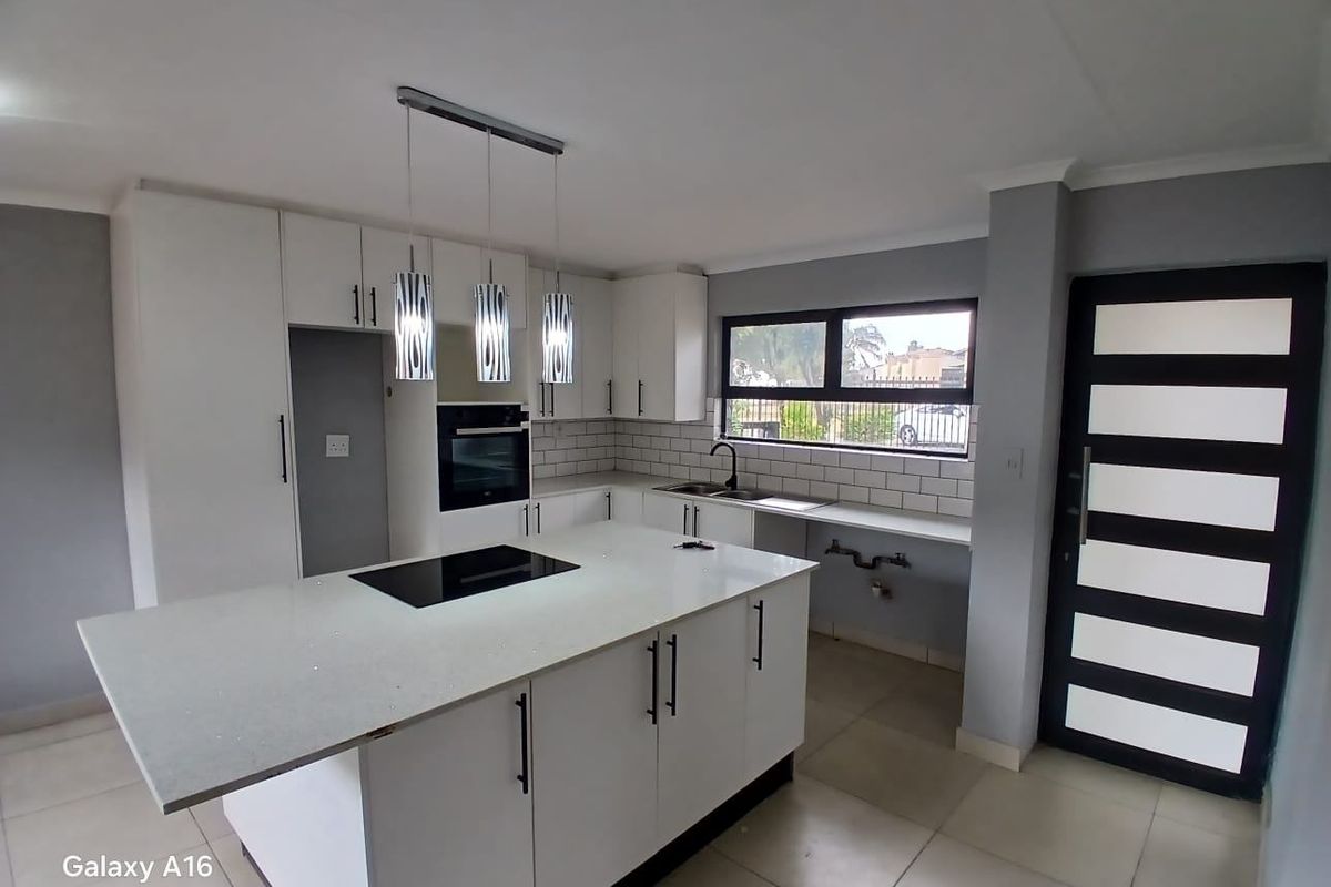 Modern kitchen featuring a central island with an integrated hob, built-in oven, subway tile backsplash, and sleek white cabinetry.