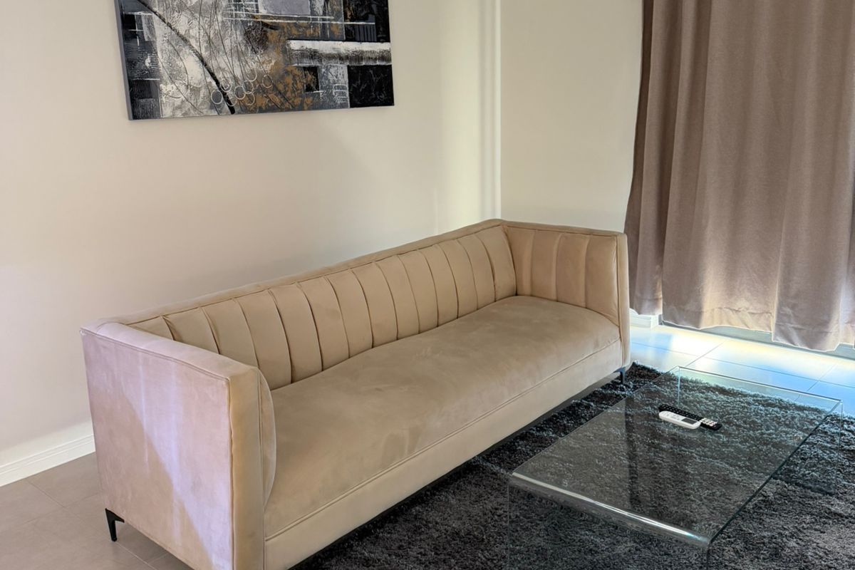A well-maintained living room featuring neutral wall tones, tiled flooring, and large window treatments, providing a comfortable and inviting space.