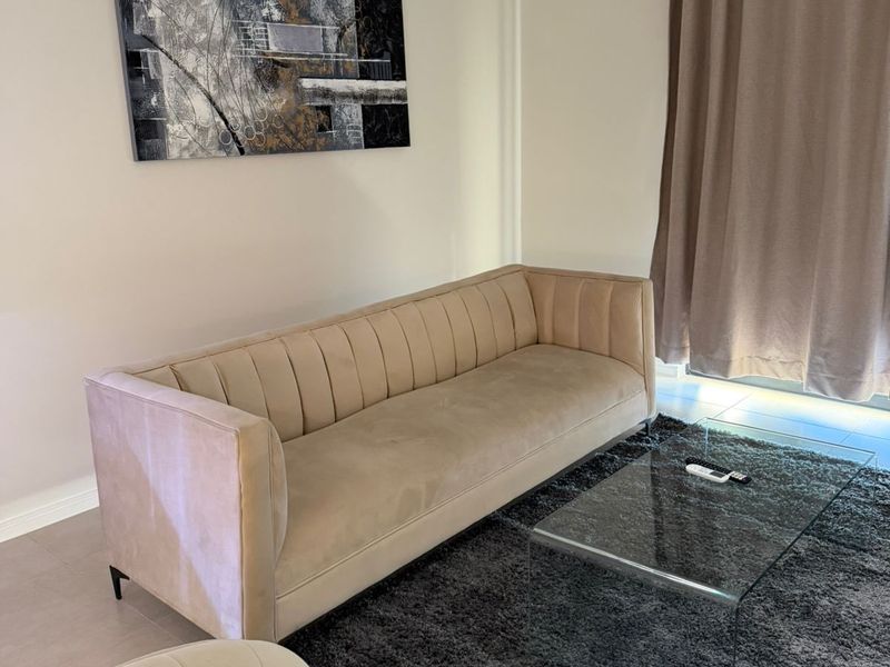 A well-maintained living room featuring neutral wall tones, tiled flooring, and large window treatments, providing a comfortable and inviting space.