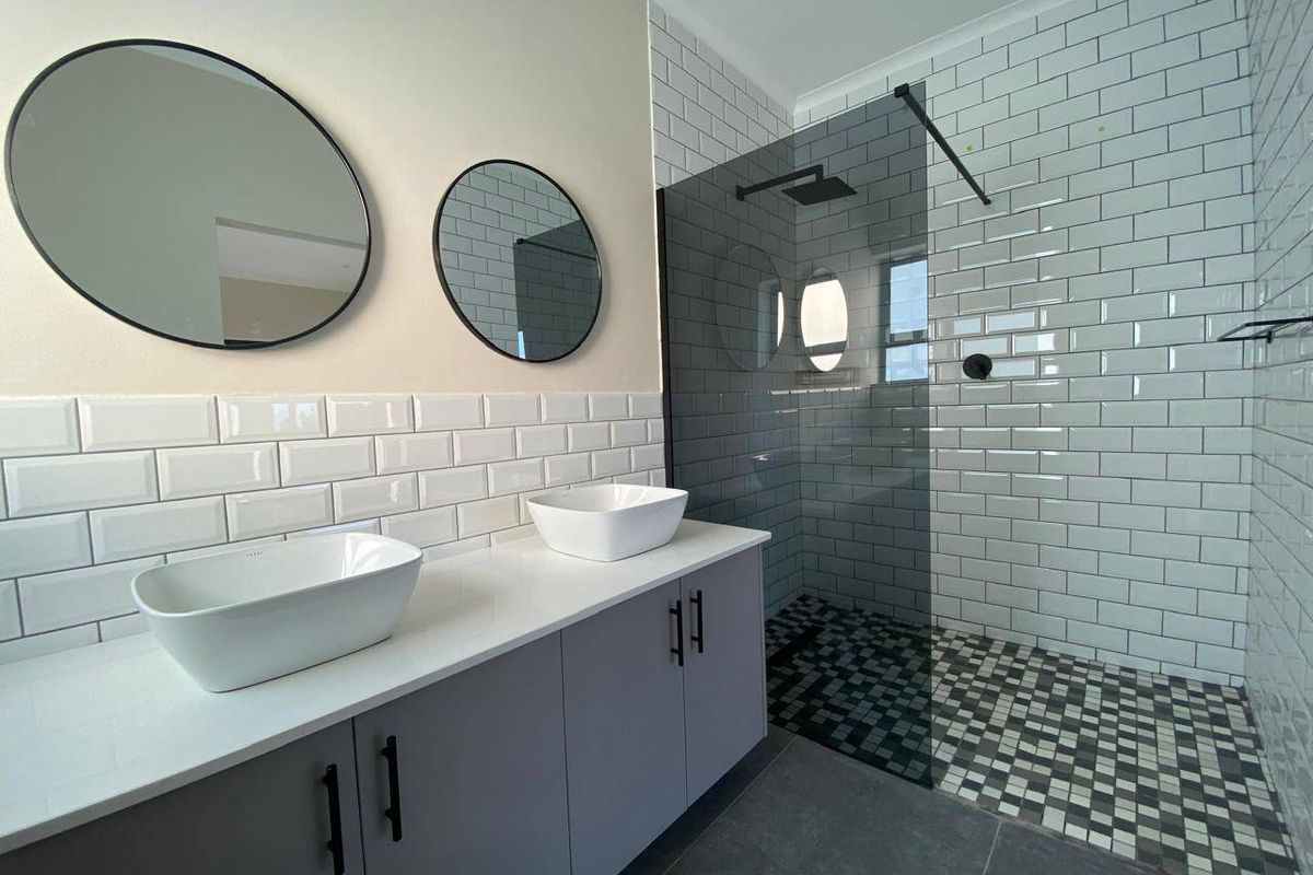 Modern bathroom featuring a double vanity with vessel sinks, subway tile backsplash, and a spacious walk-in shower with a glass screen.