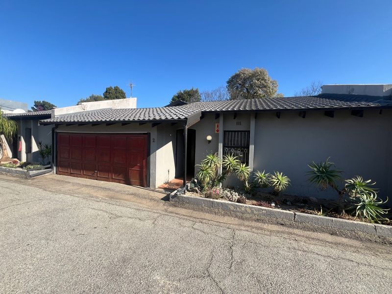 Front exterior view of a townhouse featuring a tiled roof, single garage, and a small front garden bed with a paved entrance.