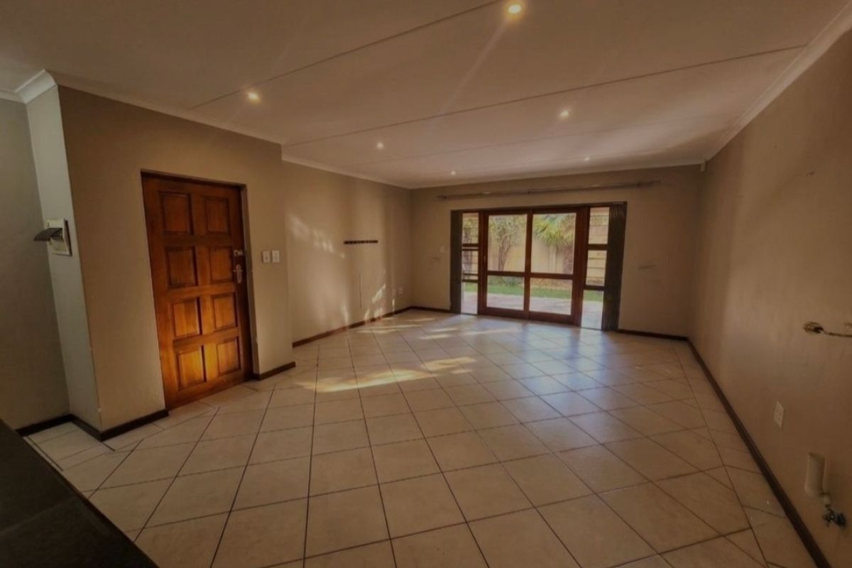 Spacious, empty living area featuring tiled flooring, recessed lighting, and large sliding glass doors providing direct access to the rear garden.