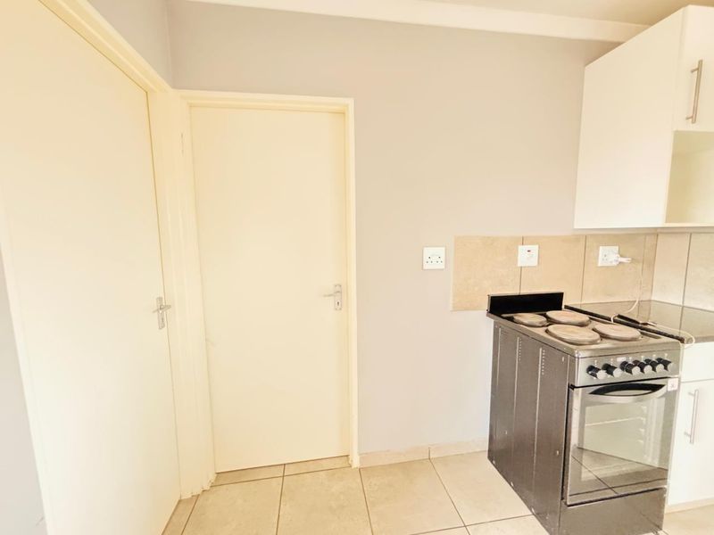 A functional kitchen area featuring tiled flooring, a tiled backsplash, and built-in cabinetry with a freestanding stove.