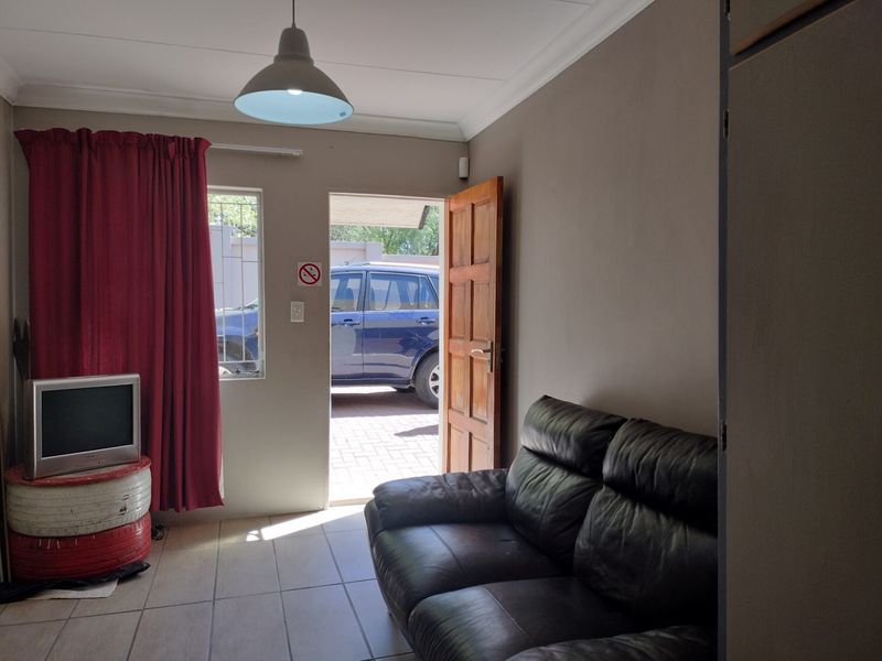 A living room area featuring tiled flooring, a pendant light, and direct access to the exterior through a wooden door.