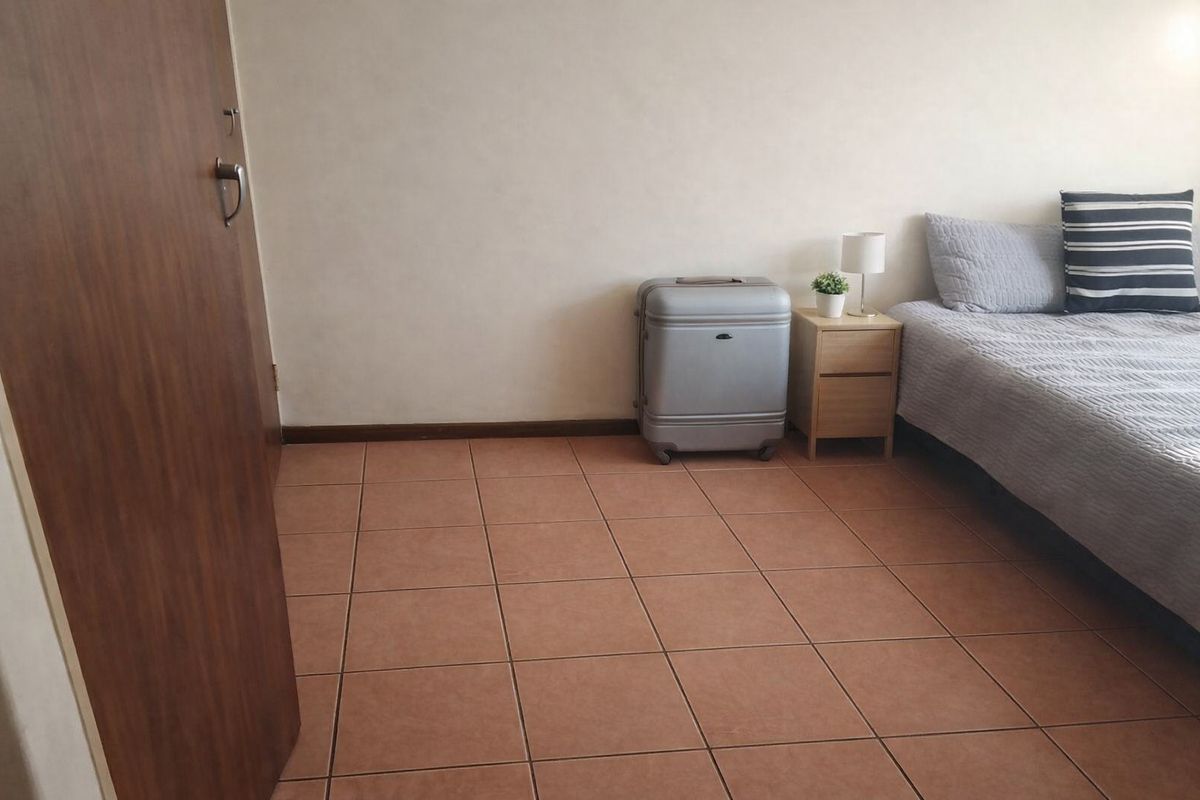 A bedroom featuring tiled flooring and a neutral wall finish, providing a simple and functional living space.