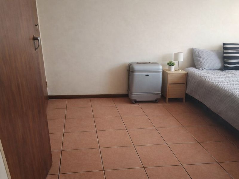 A bedroom featuring tiled flooring and a neutral wall finish, providing a simple and functional living space.