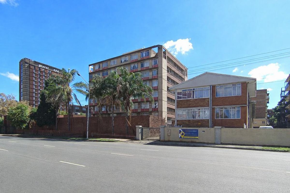 Street view of a multi-story apartment building complex featuring brick facade construction and perimeter boundary walling.