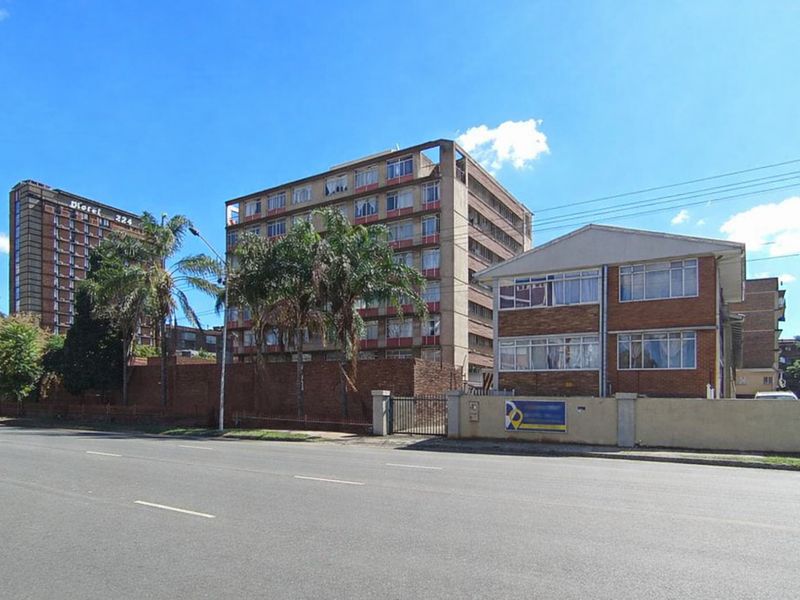Street view of a multi-story apartment building complex featuring brick facade construction and perimeter boundary walling.