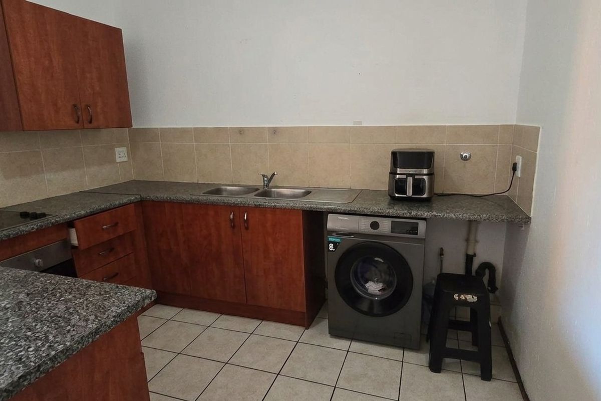 A functional kitchen featuring granite countertops, a double basin sink, built-in oven, hob, and tiled backsplash with ample cabinetry for storage.
