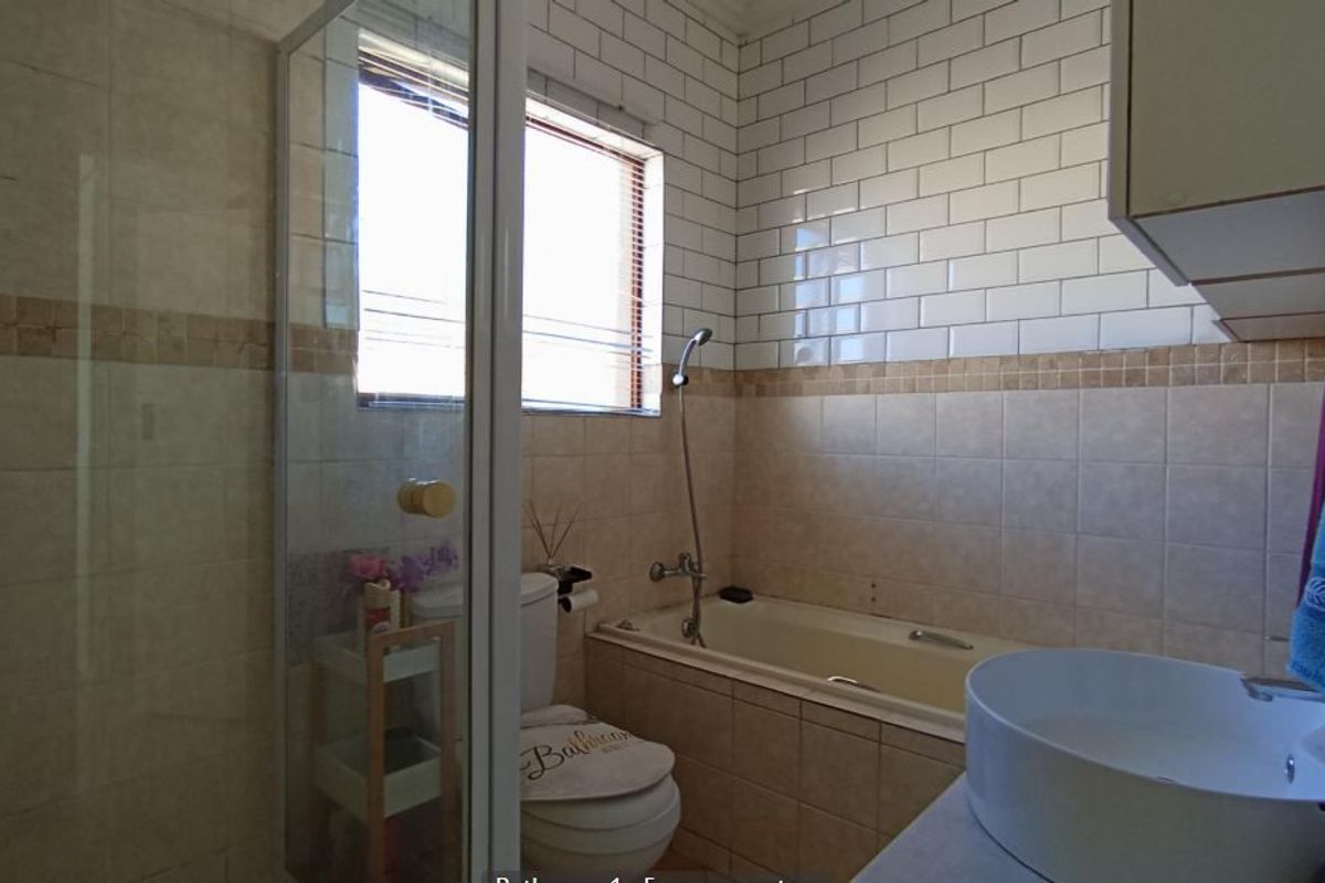 A functional bathroom featuring a shower enclosure, bathtub, toilet, and a modern vessel sink with subway tile accents.