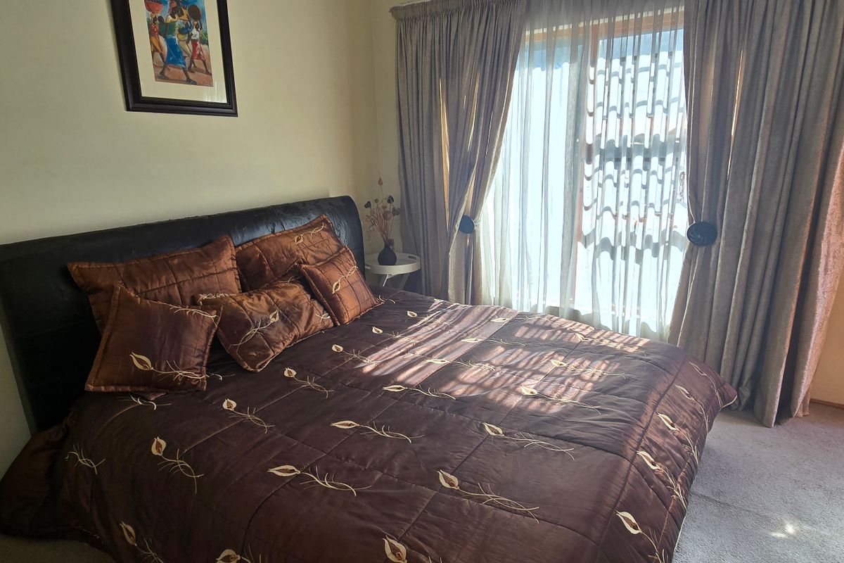 A bedroom featuring carpeted flooring, a built-in cupboard, and a sliding glass door providing natural light.