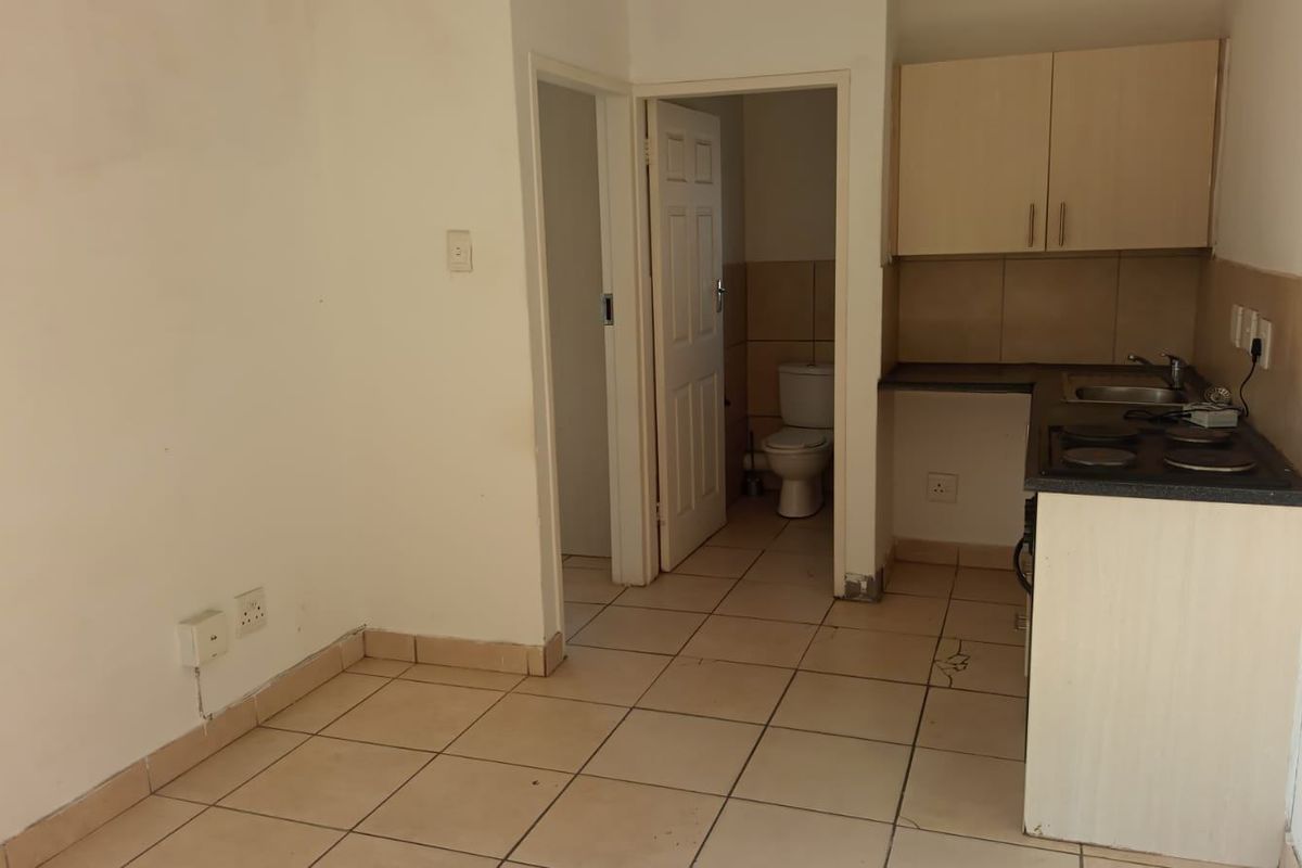 Open plan living area featuring a compact kitchen with built-in cabinetry and hob, adjacent to a separate bathroom with a toilet.