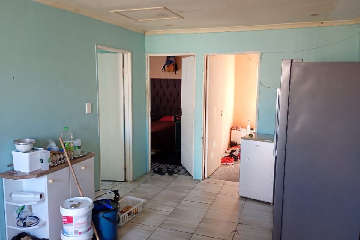 An interior living space featuring tiled flooring and access to adjacent rooms, currently requiring cosmetic updates and wall repairs.