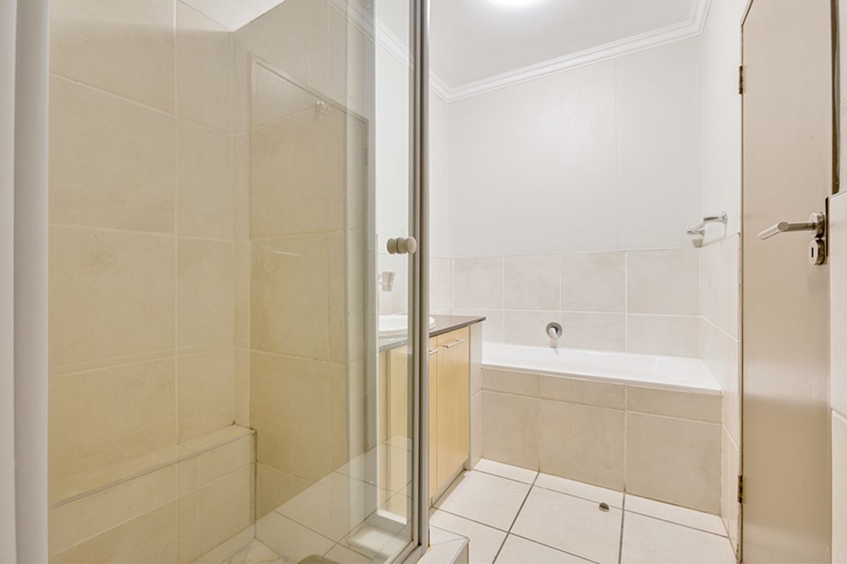A functional bathroom featuring a built-in bathtub, a separate glass-enclosed shower, and a vanity cabinet with a basin.