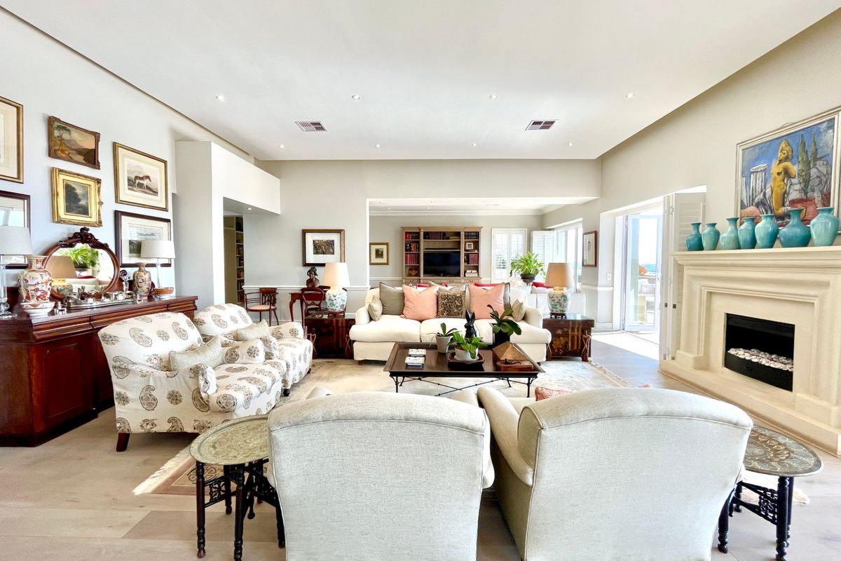 Spacious living room featuring a stone fireplace, recessed lighting, and hardwood flooring, with seamless access to an outdoor area through glass sliding doors.