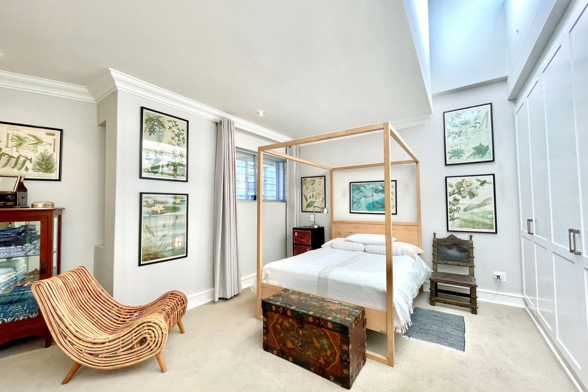 Spacious bedroom featuring high ceilings with a skylight, neutral carpeting, and extensive built-in cabinetry for ample storage.