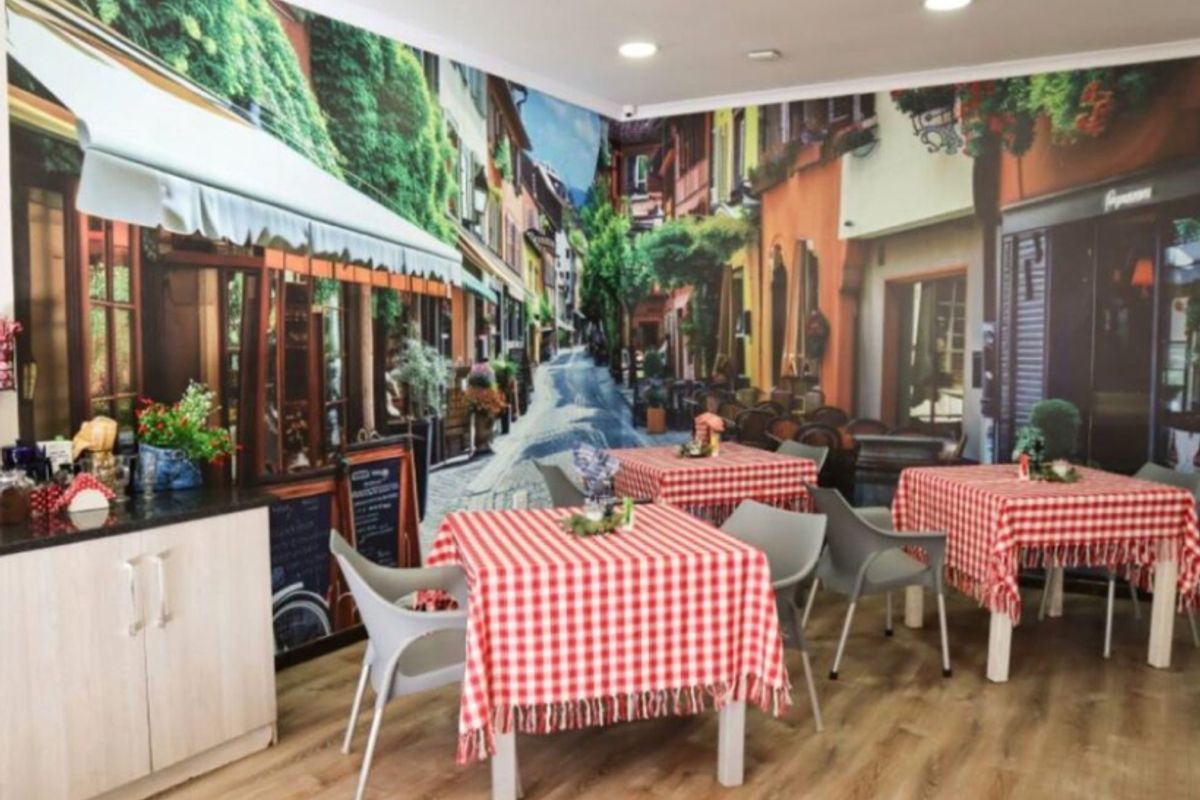 Commercial dining area featuring wood-look laminate flooring, recessed lighting, and a decorative wall mural, suitable for a cafe or restaurant setting.