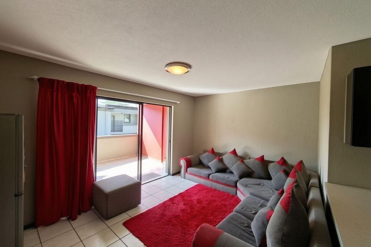 A living room featuring ceramic floor tiles and a sliding glass door providing access to an outdoor balcony area.