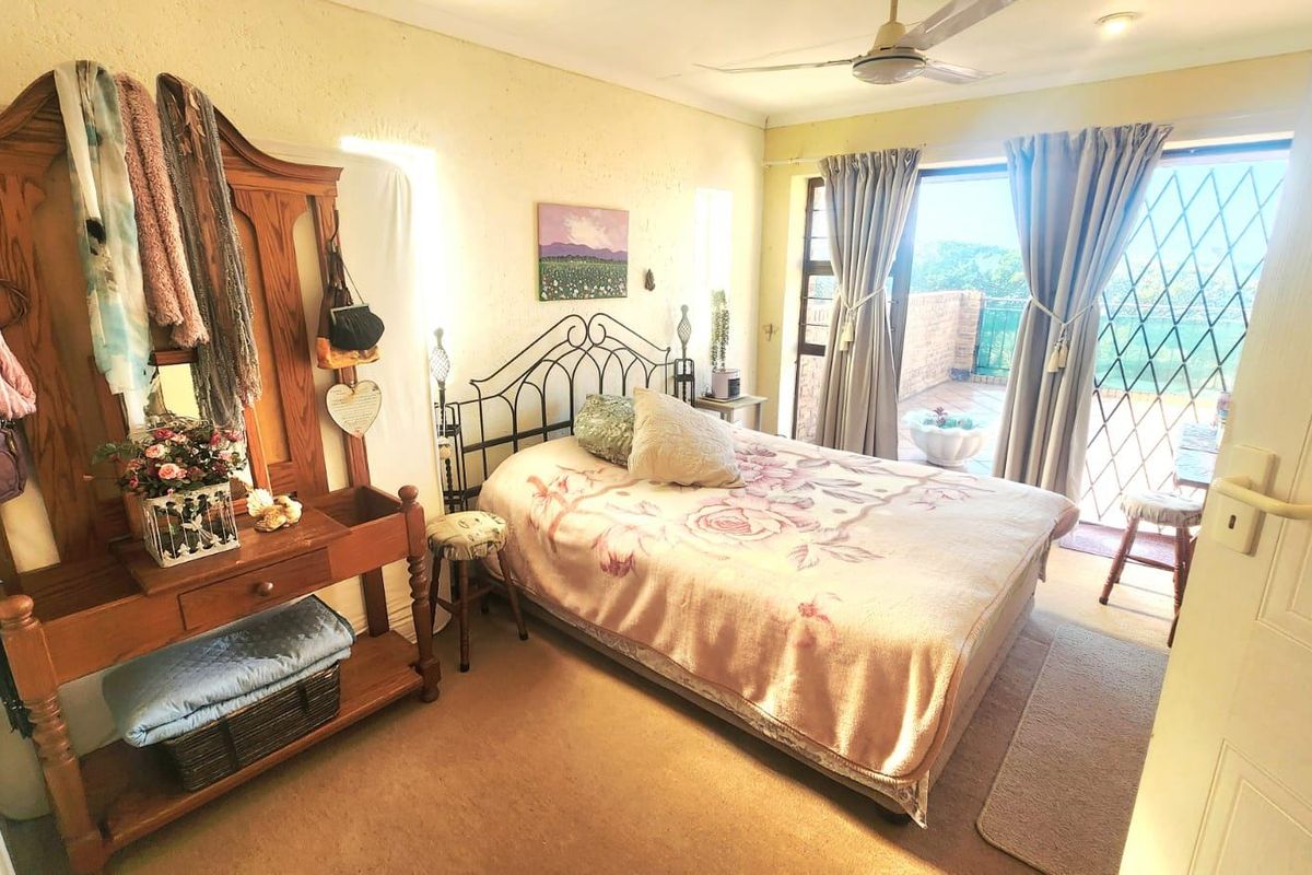 A bedroom featuring carpeted flooring, a ceiling fan, and a sliding glass door providing access to an outdoor patio area.