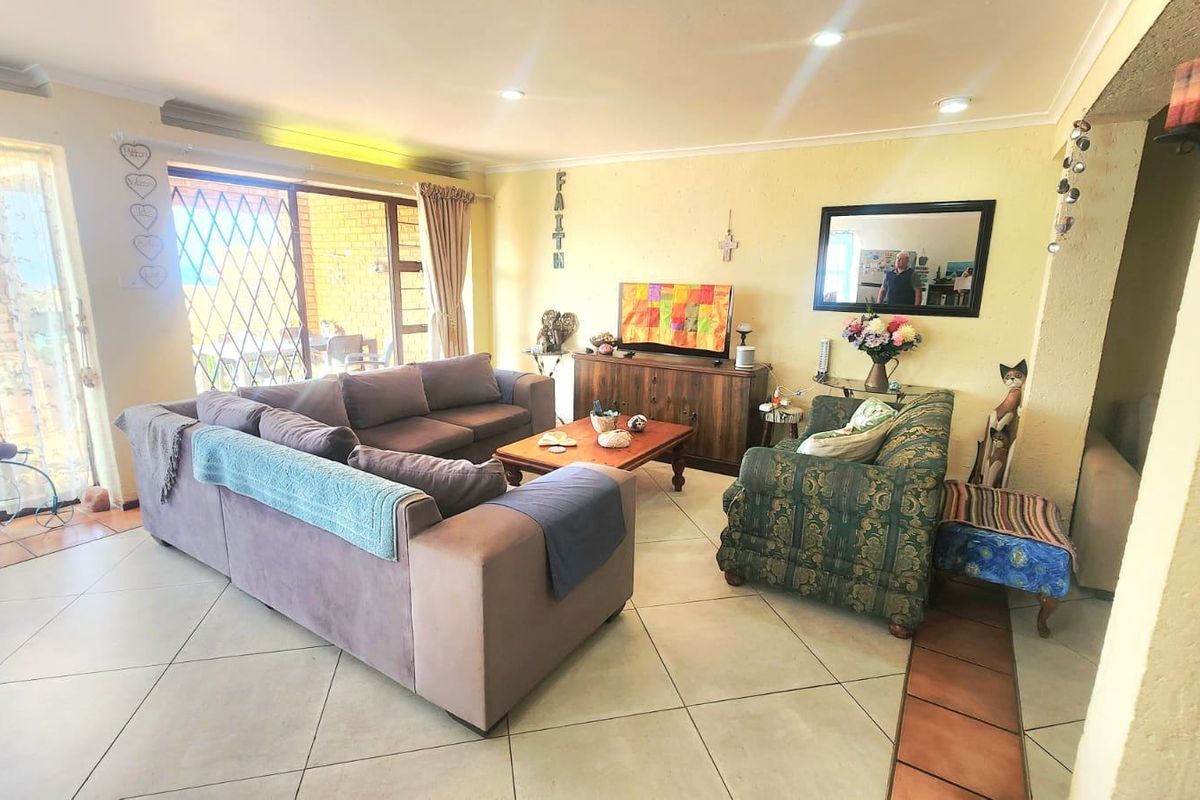 Spacious living room featuring tiled flooring, recessed downlighting, and a large sliding glass door providing access to the outdoor patio area.
